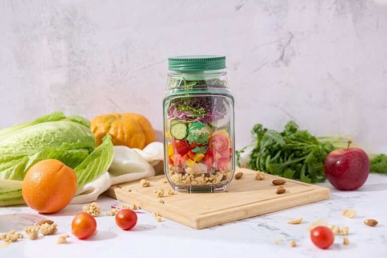 “Prepara salad pod filled with colorful layered salad on a cutting board surrounded by fresh vegetables.”